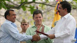 President Lobo (l) and former president Zelaya (r) shake hands as Colombian President Juan Manuel Santos (m) applauds