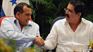 Honduran President Porfirio Lobo (left) and former president Manuel Zelaya (right) shake hands in Managua on 22 May 2011