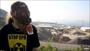 A protester wearing a gas mask stands in front of the construction site of the third-generation European Pressurised Water nuclear reactor (EPR) in Flamanville, during an anti-nuclear demonstration, on 23 April, 2011