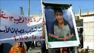 An image grab taken from YouTube on May 28, 2011 showing a protester holding a picture of Hamza al-Khatib