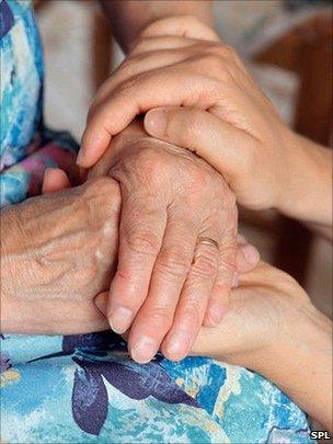 home help carer holding hands with a patient