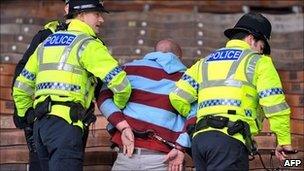 A football fan being led away in handcuffs