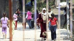Refugees walk behind the fence of a refugee camp in the Turkish town of Yayladagi in Hatay province, close to the Syrian border, on Thursday