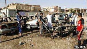 Residents gather around the remains of a vehicle used in a bomb attack, a day after blasts occurred in the Iraqi city of Ramadi (archive shot)