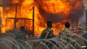 Armed men walk past burning houses in Abyei (28/05/11)