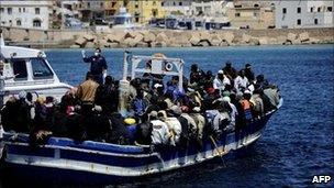 Italian police escort a boat carrying migrants from Libya into Lampedusa, 9 April