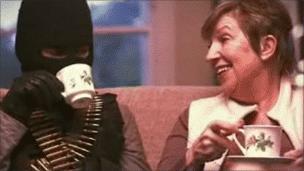 Still from MoD video showing mother having tea with man in balaclava