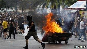 Protesters run away from tear gas canister and a burning barricade during clashes with riot police in Athens' central Syntagma (Constitution) Square, 15 June 2011