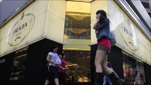 Pedestrians walk past a Prada shop in Hong Kong