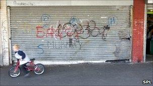 A child rides past a closed shop on a bicycle