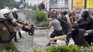 Masked demonstrators and riot police clash near the Greek parliament in Athens