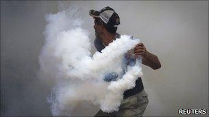 A relative of inmates from the El Rodeo prison throws a tear gas canister back during a riot (18 June 2011)