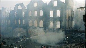 Firemen damp down shops destroyed by a firebomb in Armagh, County Armagh