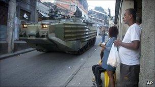 Residents look out from a shop entrance as Brazilian marines pass in an armoured vehicle, Mangueira, Rio de Janeiro, Brazil (19 June 2011)