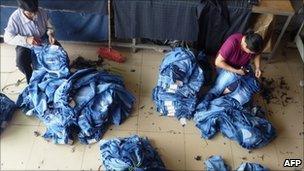 Workers stitch jeans at a small factory in Zengcheng on June 15, 2011