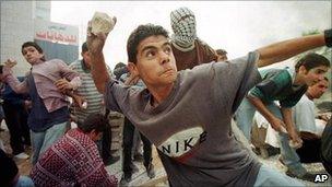 A Palestinian youth pelts Israeli soldiers with stones during clashes outside the West Bank town of Ramallah in Dec 1998.