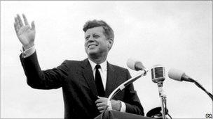 John F Kennedy waving from podium