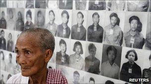 A survivor of the Khmer Rouge regime stands in front of portraits of victims at the Tuol Sleng (S-21) genocide museum in Phnom Penh