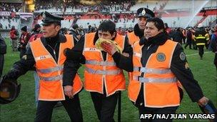 A policeman wounded by angry River Plate supporters is escorted off the field by fellow officers at the end of the match (26 June 2011)