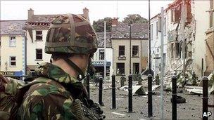 A solider stands in front of bombed building