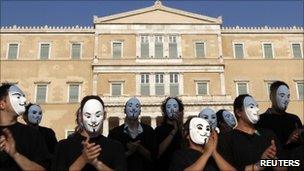 Demonstrators wearing masks protest against Greek austerity economic measures and corruption in front of parliament in Athens