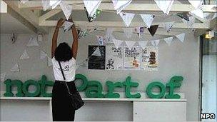 A woman hangs bunting at Not Part Of