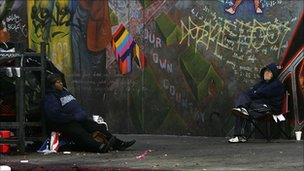 Homeless men sitting in front of mural