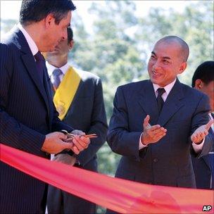 Cambodian King Norodom Sihamoni, right, introduces French Prime Minister Francois Fillon, left, cut a ribbon at a temple, northwest Phnom Penh, Cambodia, July 3, 2011