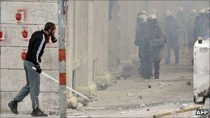 A demonstrator stands behind a wall as protesters clash with riot police during a 48-hour general strike in Athens on June 29, 2011