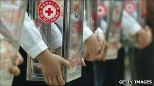 Workers of the Hainan Red Cross hold collection boxes during a fundraising event for tsunami relief on January 11, 2005 in Haikou, China