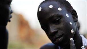 A South Sudanese boy, part of a cultural troupe, marks his face with chalk - January 2011