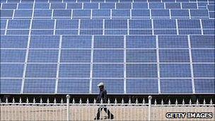 Man walking in front of solar panels