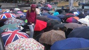 Umbrellas go up in another downpour in Trafalgar Square