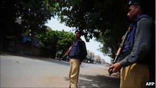 Pakistani policemen stand guard in a deserted street in a western neighbourhood affected by the political violence in Karachi on July 7, 2011