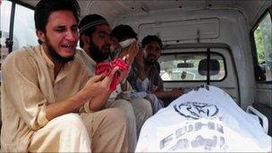 Relatives of a person killed by political violence mourn over the body inside an ambulance at the Jinnah Postgraduate Medical Centre in Karachi on 6 July 2011