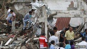 People surround a house that was damaged after being hit by a bus that detonated in Toribio, in Cauca province, 9 July 2011