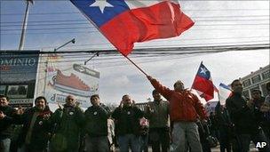 A worker from Chile's state-owned copper mining company Codelco, waves a Chilean flag next to co-workers during a strike in Los Andes, Chile, 11 July 2011.