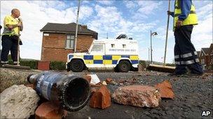 Workers sweep debris and rubbish from a street as a large clean up operation gets underway in Ardoyne