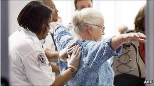 A woman being inspected by a TSA employee at a US airport