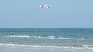 The Portland Coastguard helicopter assisting the RNLI at Boscombe beach, Bournemouth