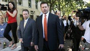 Roger Clemens walking with a lawyer and members of the press outside of a courthouse