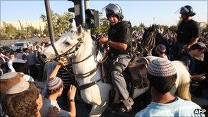 Mounted police officer surrounded by religious Jewish demonstrators outside Supreme Court.