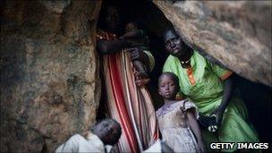A terrified mother looks out of a cave as she takes shelter from an aircraft flying over the hills surrounding Lwere in Sudan's Nuba mountains on 1 July 2011