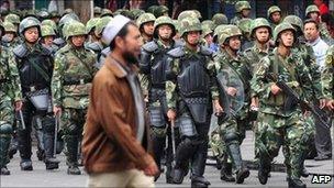 Armed Chinese soldiers march on patrol as a Uighur man crosses the street in Urumqi on July 15, 2009 in north-west China's Xinjiang province