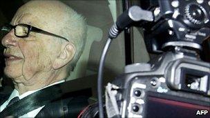 Photographers take pictures of News Corporation Chief Rupert Murdoch through his car window as he leaves his London home on July 14, 2011