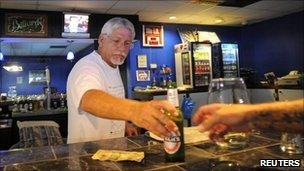 Business owner Stephen Gaughran (C) sells a beer to a regular customer from behind the bar inside his billiard hall in Titusville, Florida July 6, 2011