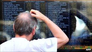 A man looks at a board outside Milan's stock exchange