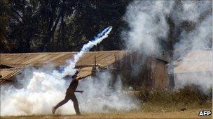 A protester throws back a teargas canister fired by police during an anti government demonstration in Lilongwe on July 20, 2011