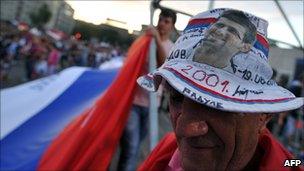 A fan of Serbian tennis player Novak Djokovic wears a hat with his picture on