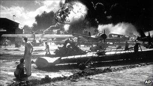 US soldiers standing near burning military aircraft during the Japanese attack on Pearl Harbor in 1941